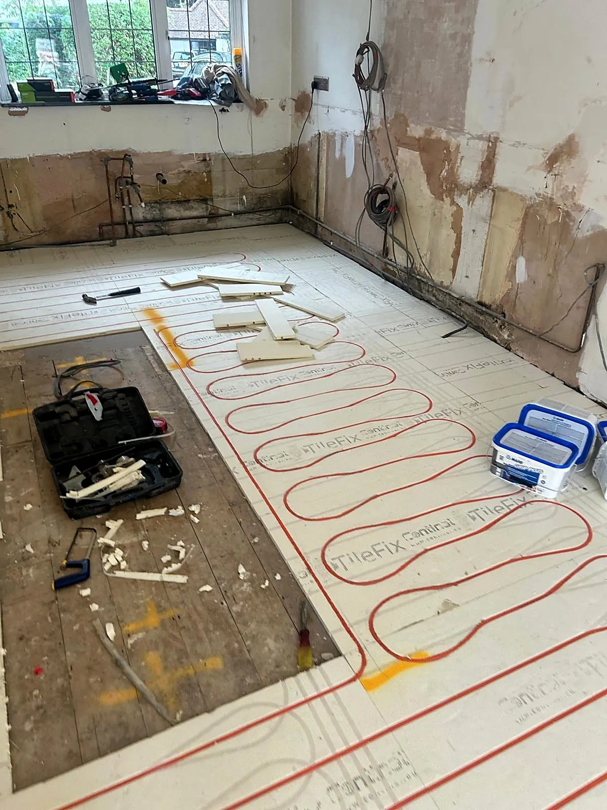 Wet underfloor heating pipes laid in insulation boards during installation, photo 1
