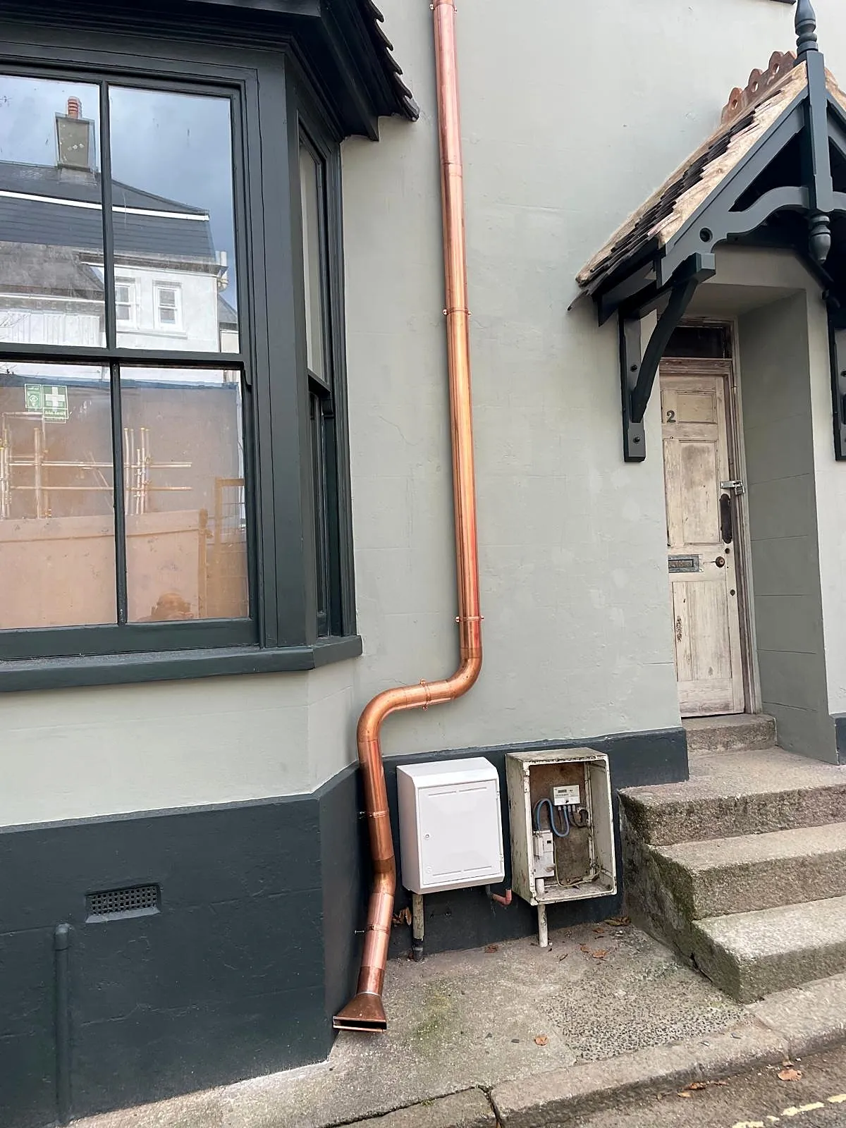 Copper downpipe with offset bends fitted to a period house front