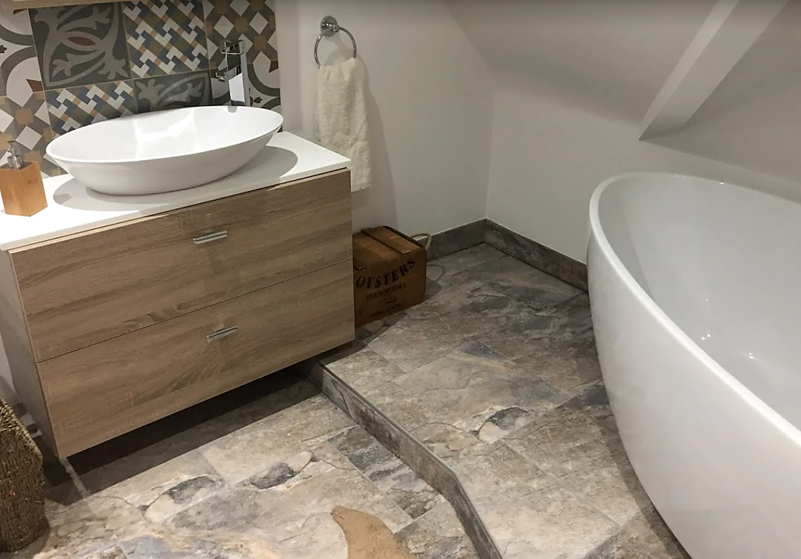 Finished bathroom with wooden vanity, vessel basin, stone-effect tiles and freestanding bath